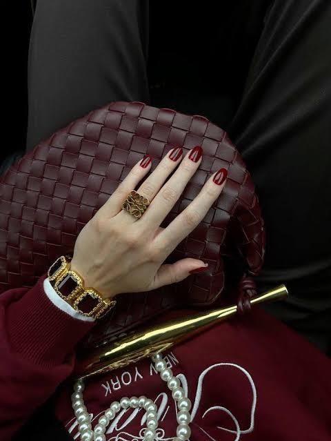 Main féminine et accessoires bordeaux